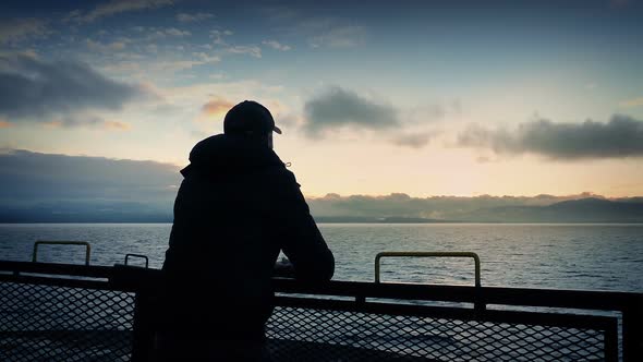 Man Looks From Back Of Ship At Sunset