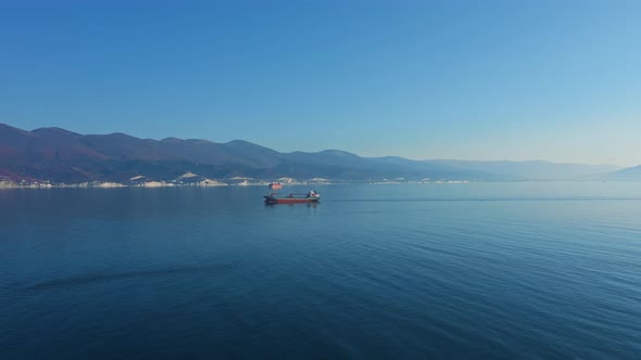 Aerial View of a Red Boat Sailing Past the Shores of a Picturesque Asian Country