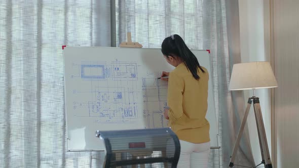 Asian Woman Engineer With A Laptop Drawing Blueprint On The Whiteboard At The Office
