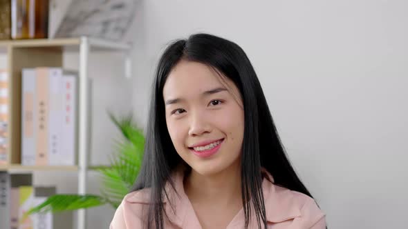 Close up smiling face of Asian black hair woman who is sitting on sofa