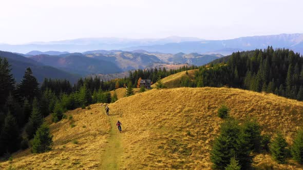 Two bikers riding down a mountain trail in autumn sunny day. MTB bike riding on track trail.