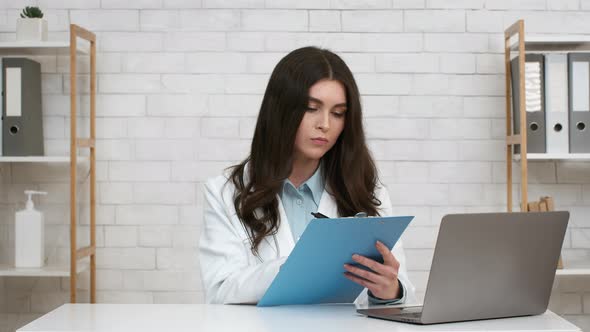 Professional Female Therapist Taking Notes Sitting At Laptop In Office