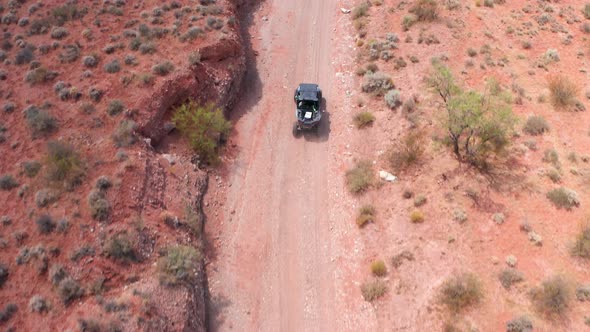 Overhead drone shot of off road vehicle driving down a dirt road in the desert.