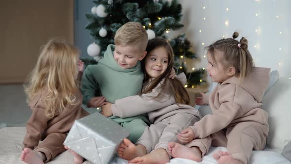 Four Children Hugging Near Christmas Tree