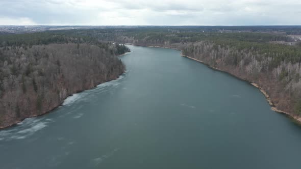 AERIAL: Nature Panorama of Frozen Lake with Forest Growing on Shores