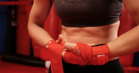 Female boxer wearing red strap on wrist in fitness studio