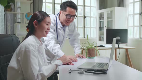 Two Asian Professional Physicians Talking, Consulting And Working On Laptop Computer