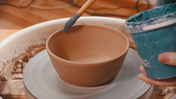 Pottery - Man Is Painting with a Brush the Clay Bowl Inside Blue