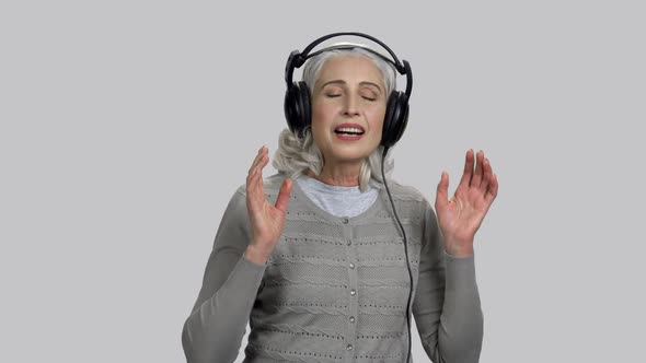 Old Lady Listening and Enjoying Slow Music with Big Headphones