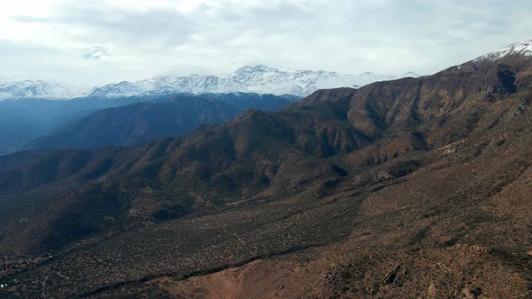 Dolly out aerial view of San Carlos de Apoquindo Park with the snowy Cerro El Plomo in the backgroun