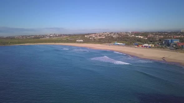 Drone flying over a beautiful beach in Sydney Australia. Waves and a sandy beach are illuminated by