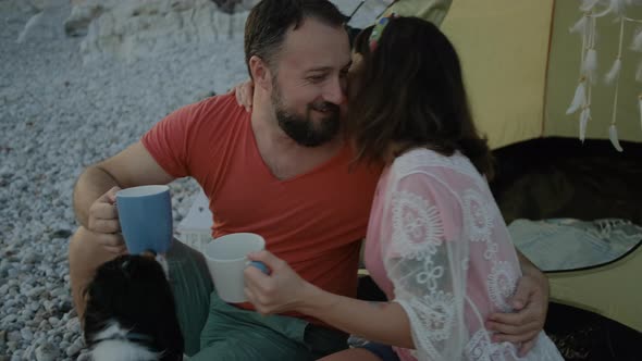 Couple drinking tea on pebble beach with Adorable dog breed king charles cavalier