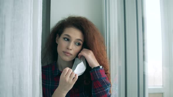 Woman Takes Off Medical Mask While Looking Through Window