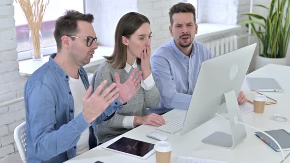 Shocked Creative Team Reacting To Failure on Desktop in Office