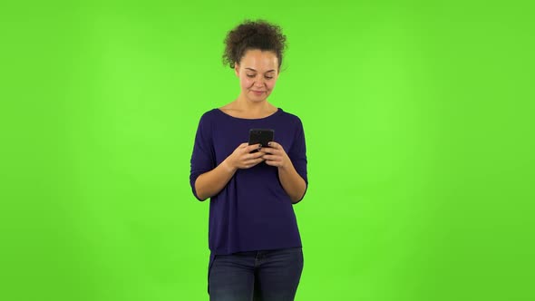 Curly Woman Smiling Woman Texting on Her Phone . Green Screen