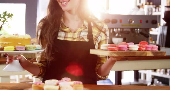 Portrait of waitress standing at counter with desserts