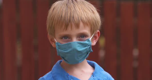 Cute little boy in a face mask turns toward the camera.