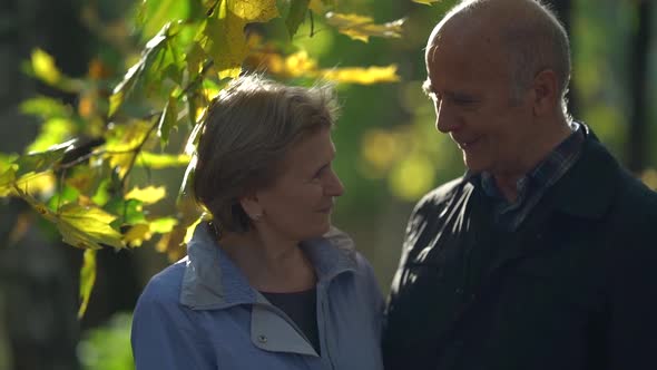 Old Married Couple, Man and Woman Are Looking To Each Other with Love, Portrait in Autumn Park