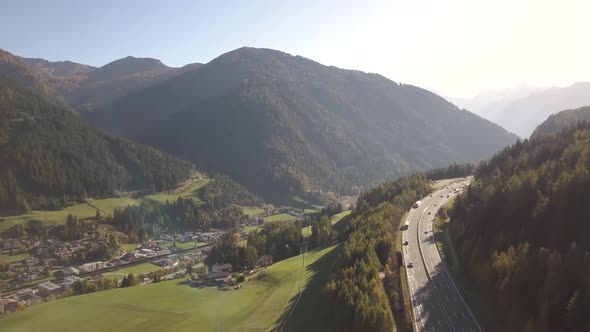 Aerial view of highway interstate road with fast moving traffic in rural area between green fields