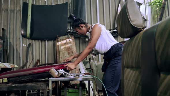 Attractive young woman mechanical worker repairing a vintage car in old garage.