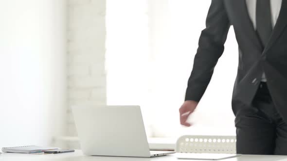 Young Businessman Coming Back Opening Laptop in Office