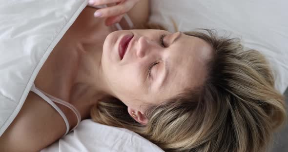 Woman Looks in Shock Under Covers While Lying in Bed