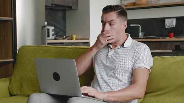 Man Is Unpleasantly Surprised and Shocked By the Bad News Seen on the Laptop Screen While Working at