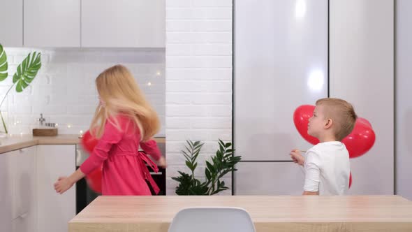 Little Boy and Girl Dancing with Red Heart Shape Balloons at Home