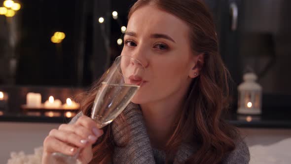 Young Woman Drinking Champagne at Home at Night