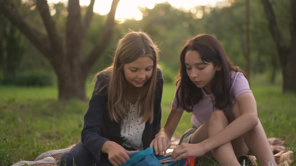 Happy Teenage Relaxed Girls Talking Sitting on Picnic in Park at Sunset Outdoors