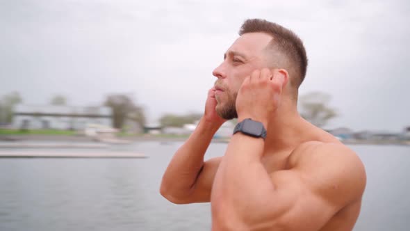 Muscular Man Naked to Torso Puts on Wireless Headphones Before Starting Workout