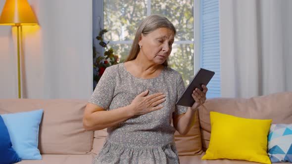 Senior Woman Sitting on Couch Calling Doctor on Video Chat Using Digital Tablet