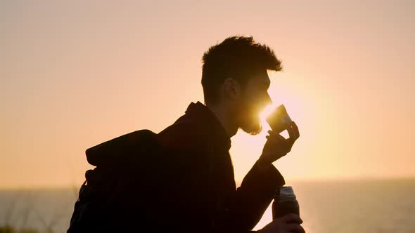 Young Man Drinking Cup Across the Sunrise Slow Motion
