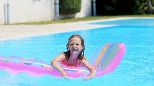 Adorable Girl with Inflatable Mattress in Outdoor Swimming Pool