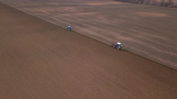 Agricultural Work in the Field, Two Blue Tractors Plow the Land