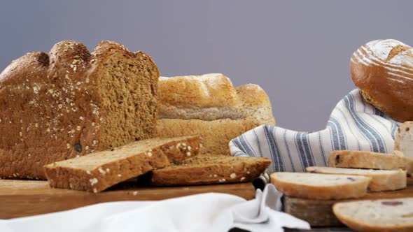 Various bread loaves with butter on wooden table