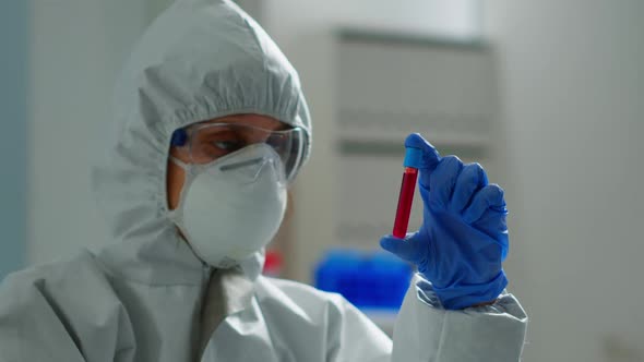 Biochemist in Coverall Holding Blood Sample Analysing Chemical Reaction