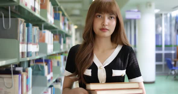 Slow motion Asian student girl with books walking in library.