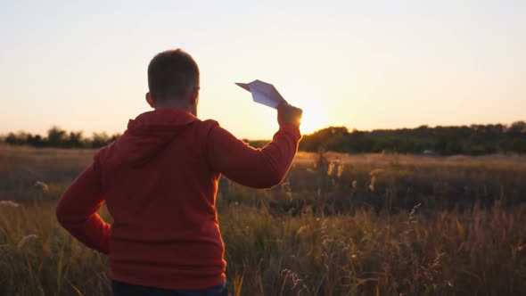 Rear View of Cute Little Child Running with a Paper Airplane Through Meadow