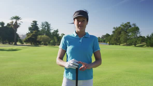 Portrait of female caucasian golf player smiling while standing with golf club at golf course