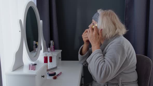 Old Senior Woman Grandmother Taking Care of Skin Near Eyes and Wrinkles, Putting Makeup on at Home