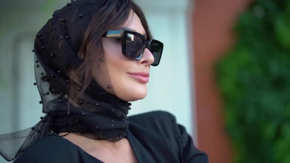 Pretty European Girl in Black Dress and Headscarf Walks Through Streets of the City