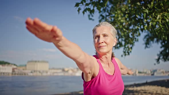 Focused Elderly Woman Stands in Pose Enjoying Yoga in Nature