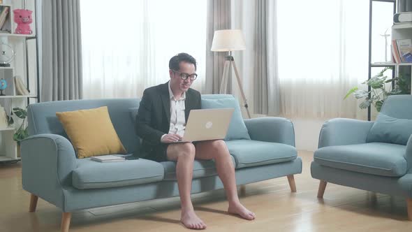 Full View Of Asian Businessman In Jacket And Shorts Having Video Call On A Laptop At Home