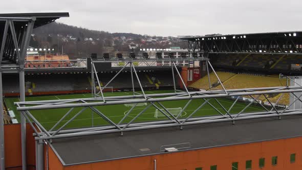 Arena exterior and green soccer field of local team on Swedish town, aerial orbit shot