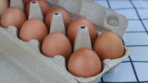 Woman hand pick up fresh chicken eggs from an egg tray.