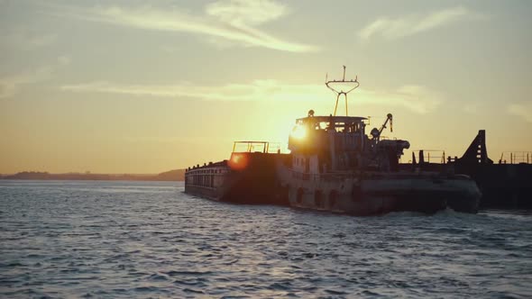 Silhouette of a Cargo Barge on a Sunset Background. Transportation of Goods By River. Beautiful