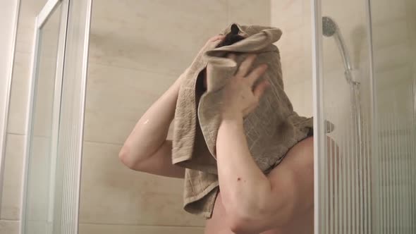 Young Man Is Wiping His Hair with a Towel Standing in a Shower Cabin