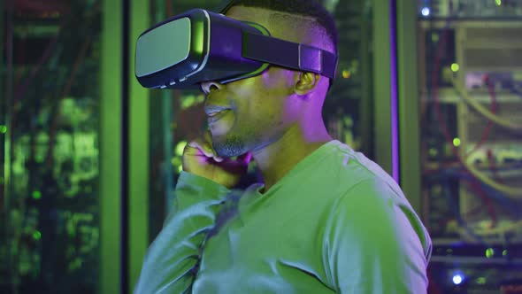 African american male computer technician using vr headset working in business server room