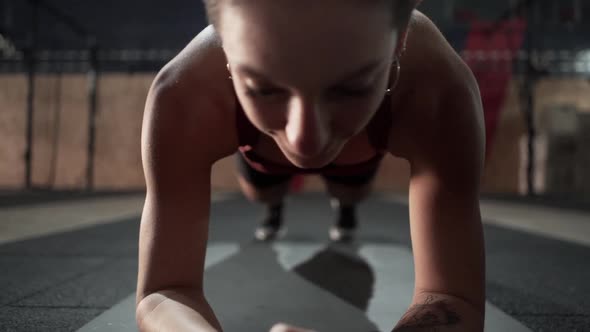 Young female doing planking exercise in gym